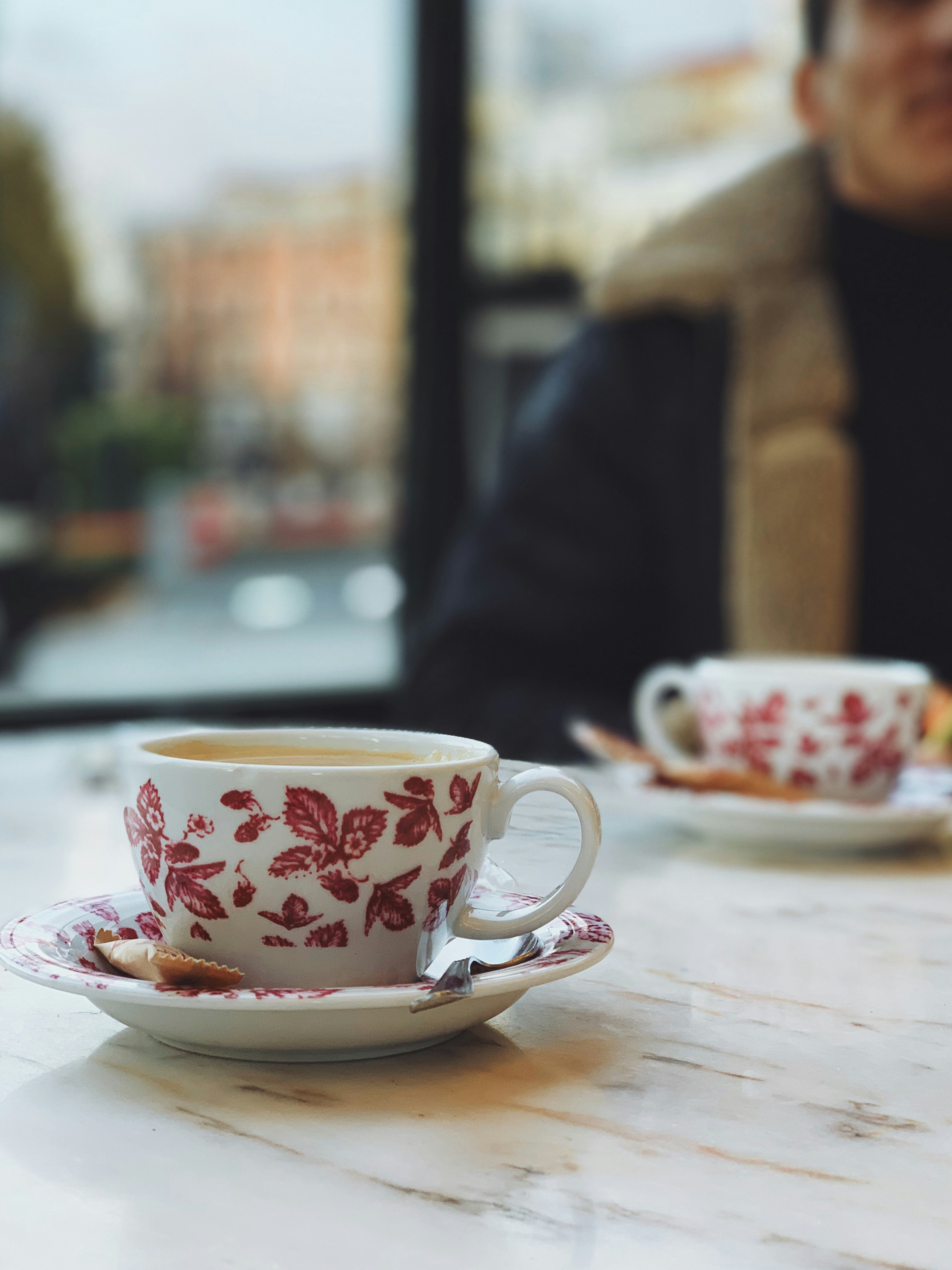 white and red floral ceramic mug on saucer