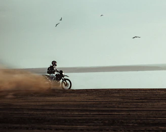 man riding on dirt bike near body of water