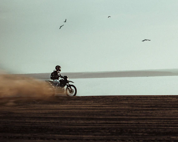 man riding on dirt bike near body of water