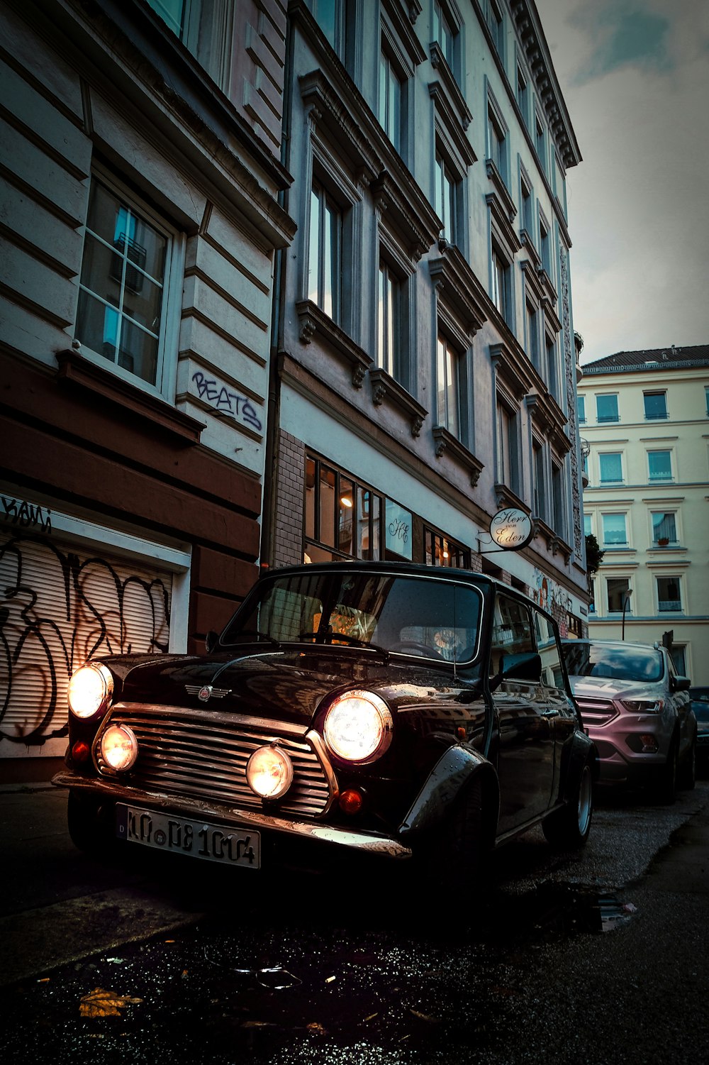 black car parked beside gray building during daytime