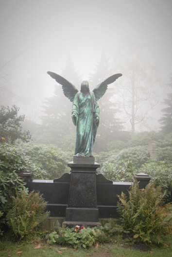 angel statue surrounded with trees