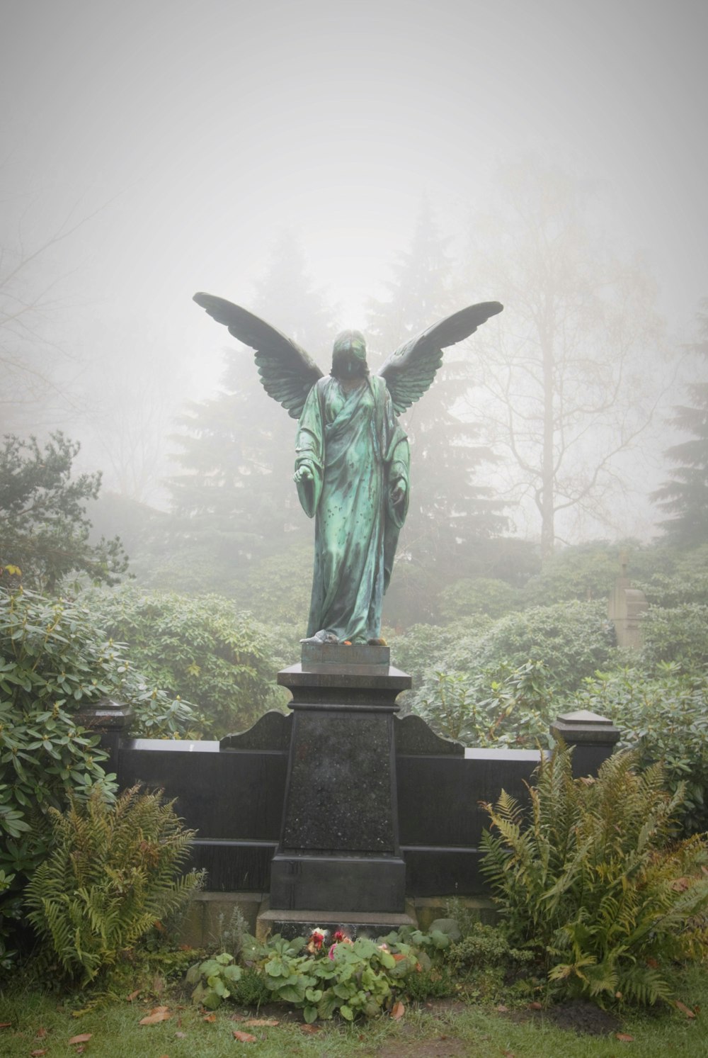 Estatua de ángel rodeada de árboles