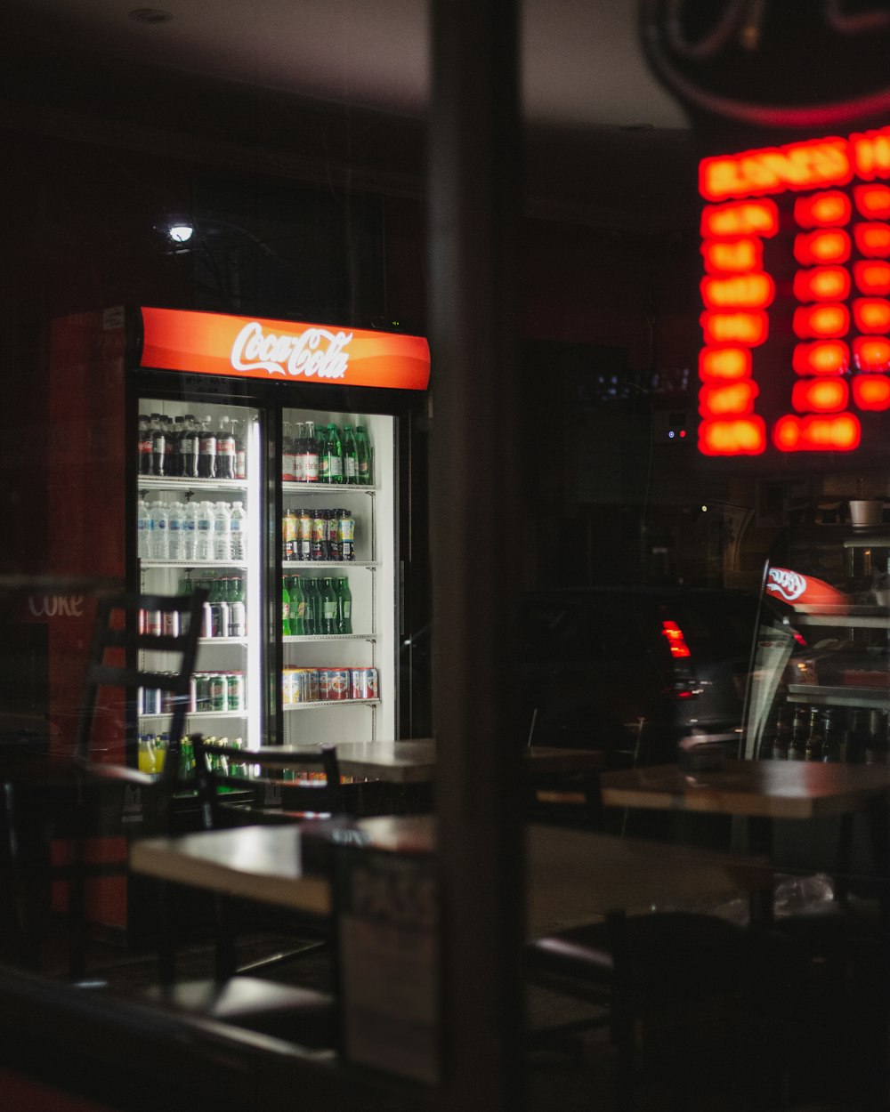 Coca-Cola beverage cooler near tables and chairs indoors