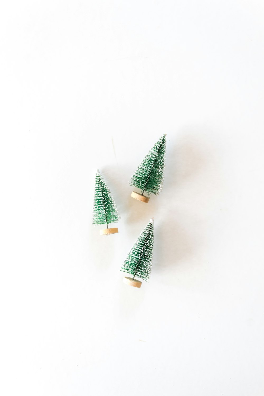 three pine tree miniatures on white surface