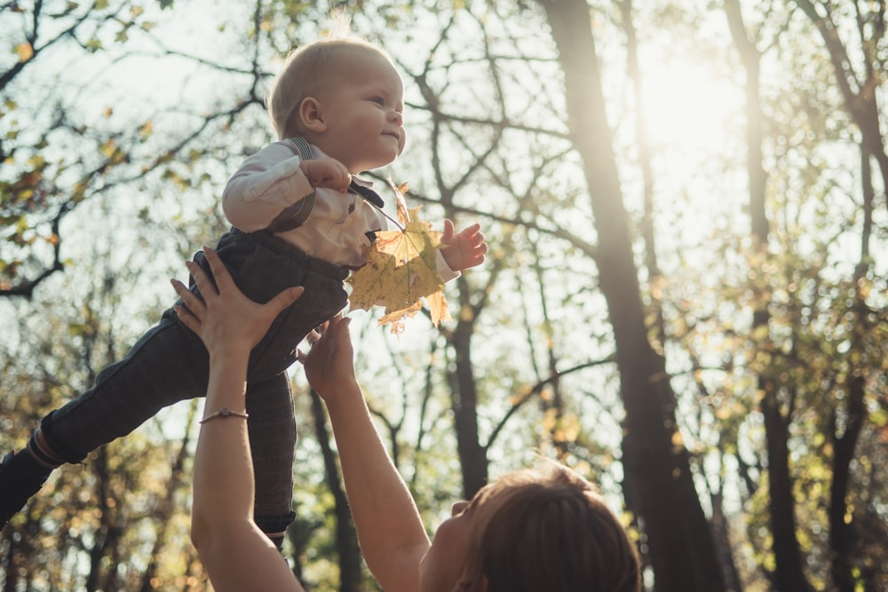 fotografia ravvicinata di donna che porta un bambino vicino all'esterno durante il giorno