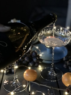 Close-up of a hand pouring golden Alsace wine into a crystal glass during a festive dinner.