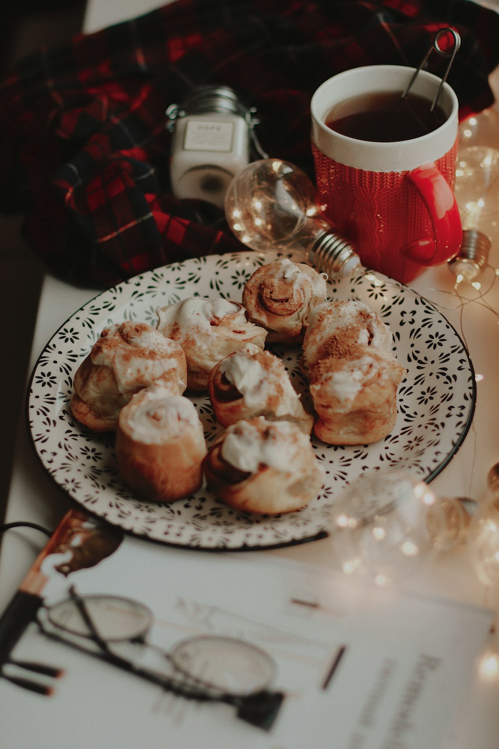 bread with cream toppings on round plate near lighted bulb and white and red ceramic mug