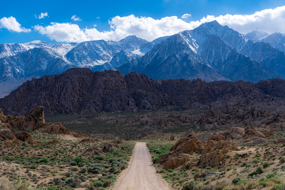 dirt road in the middle of the field near mountains