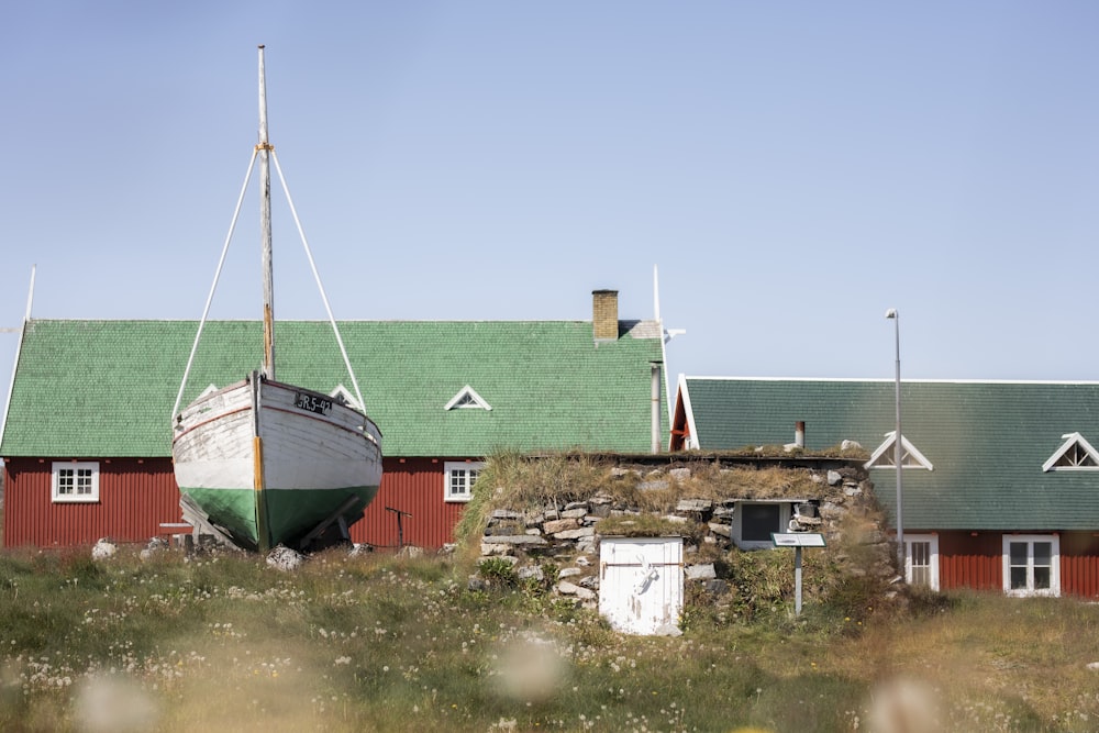 white and green boat near red house