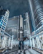 man wearing grey jacket and black pants standing on bridge