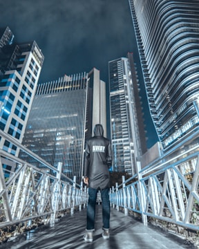 man wearing grey jacket and black pants standing on bridge