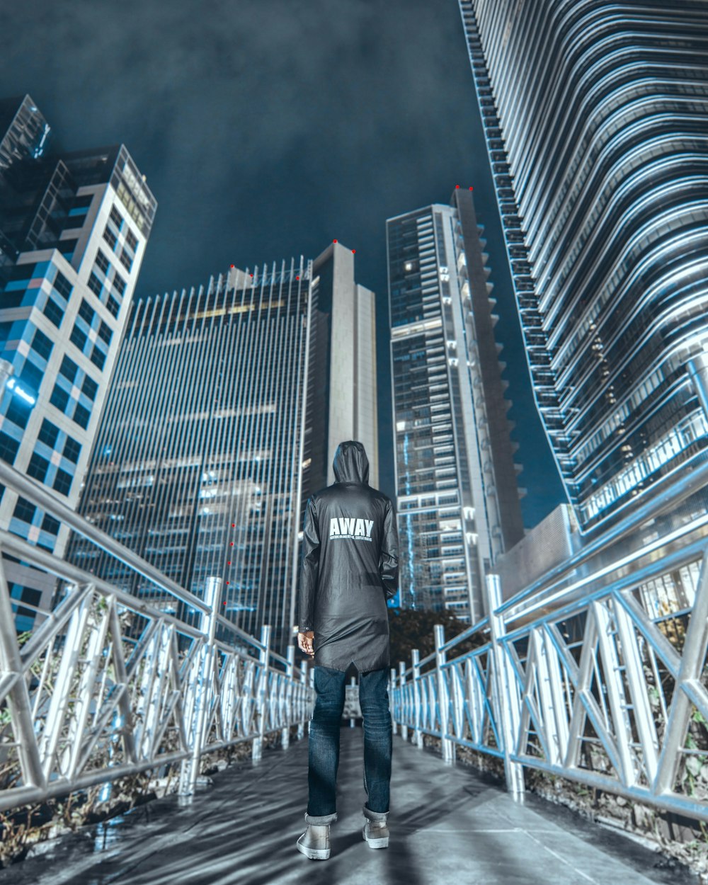 man wearing grey jacket and black pants standing on bridge