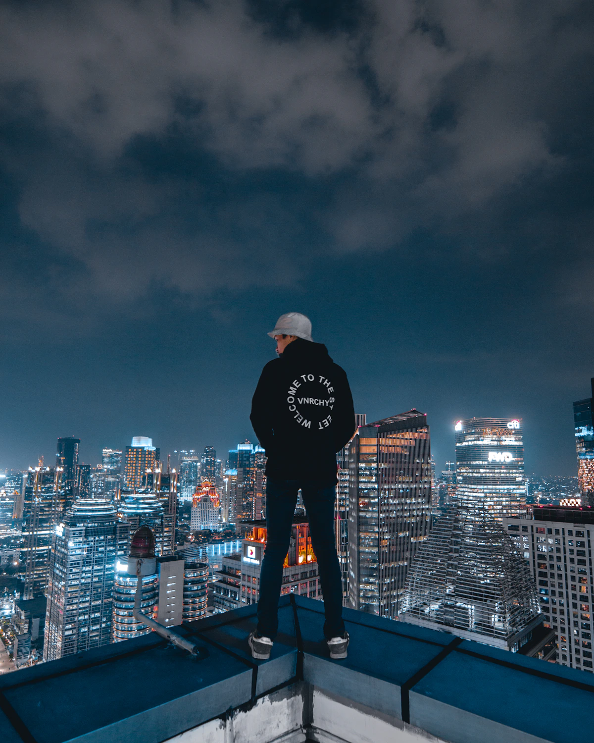 Hooded streetwear look above a night city skyline