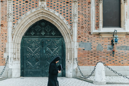 woman holding book while walking near building in St. Mary's Basilica Poland