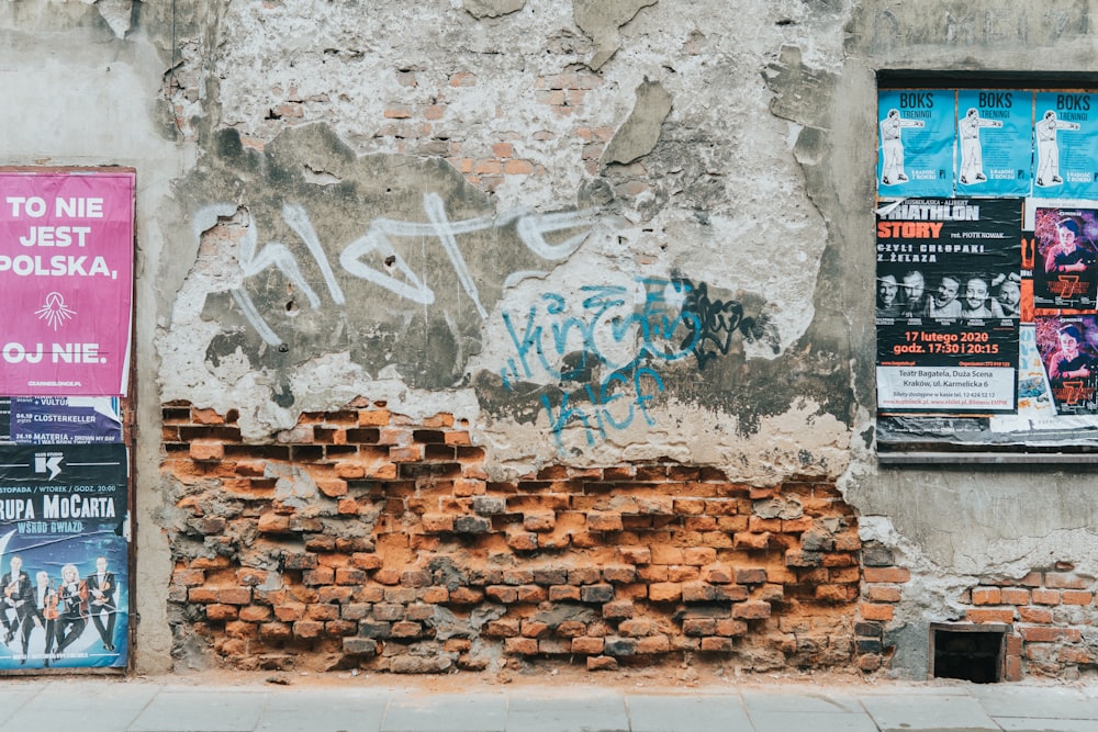 a brick wall with graffiti and posters on it