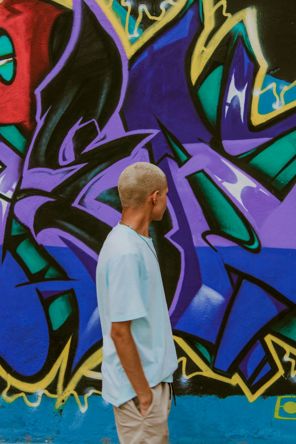 man looks and stands in front of the graffiti wall