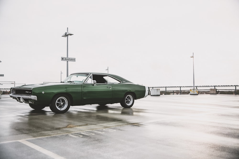 Muscle Car verde en el estacionamiento mojado