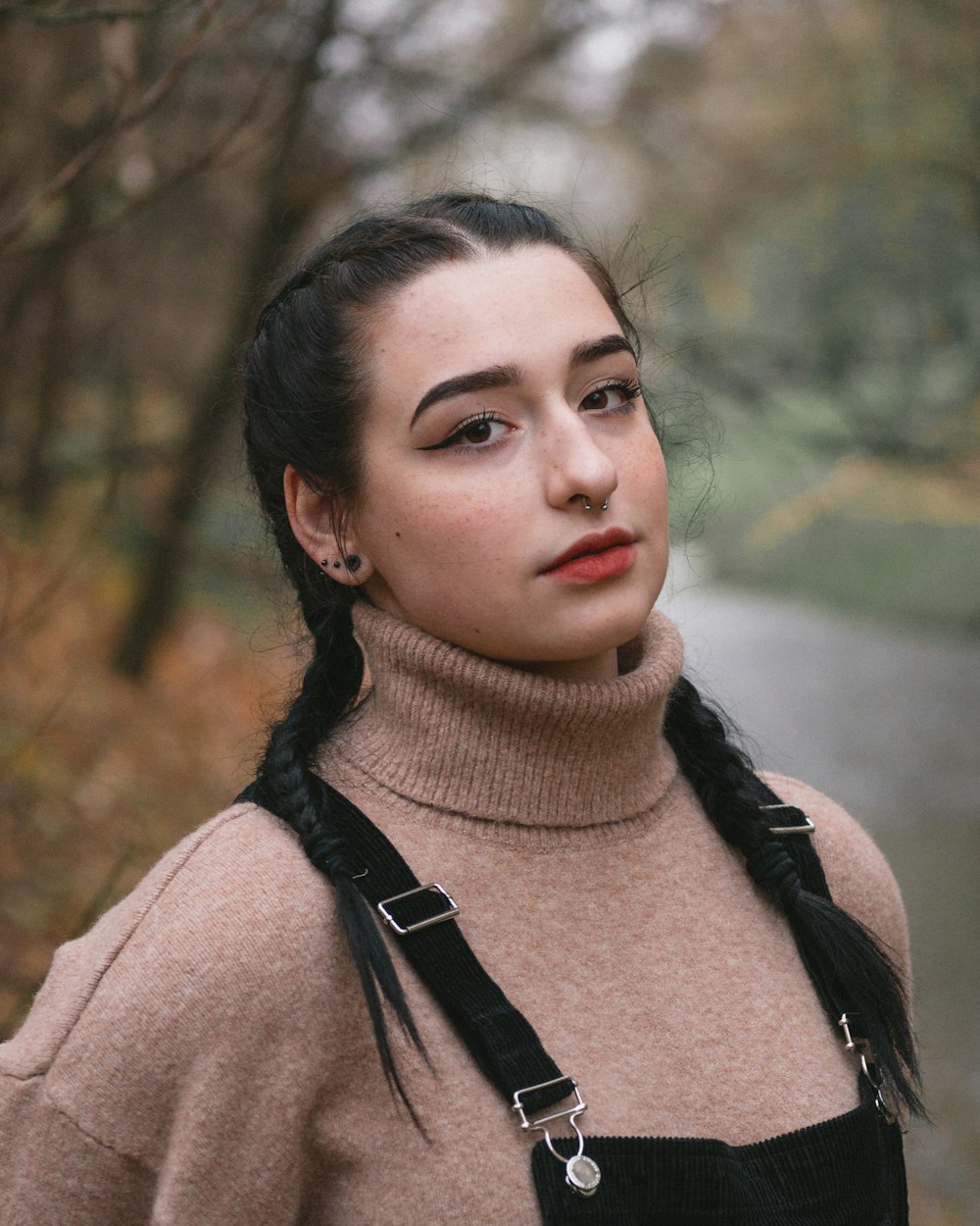 woman in black dungaree top and brown turtleneck sweater