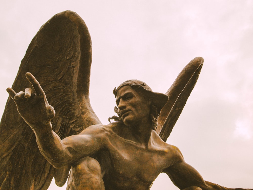 homem com estátua de concreto da asa do anjo