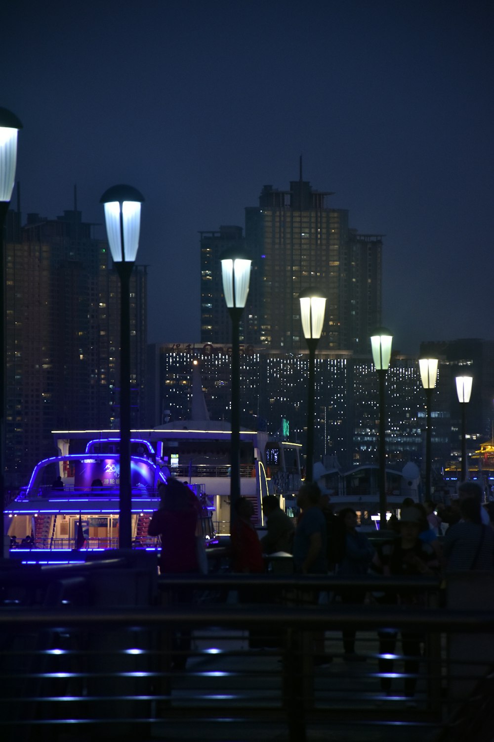 people walking on pathway near buildings and different vehicles on road during night time