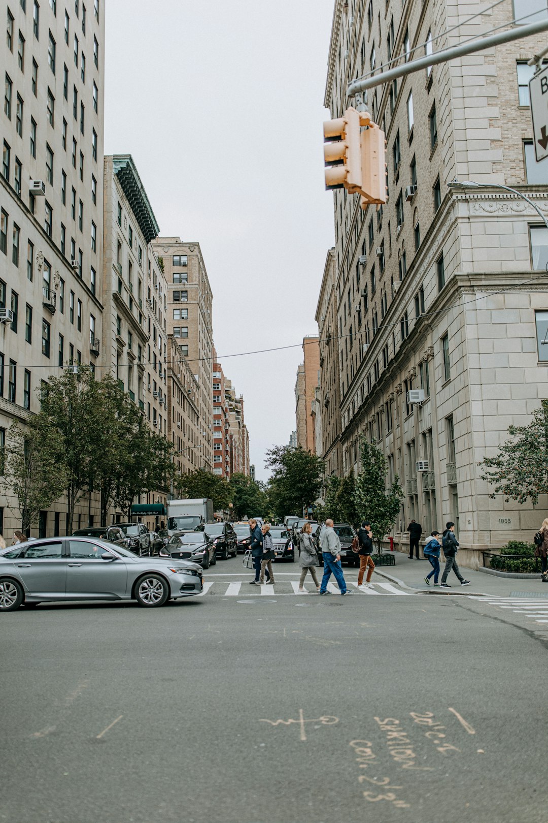 people crossing on pedestrian lane near buildings during daytime