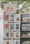 A display stand holds various art prints and posters in frames. Each print features colorful and diverse artwork, including cityscapes and famous magazine covers. A sign on top reads '$6 with frame 8x10'. The background shows leafy trees.