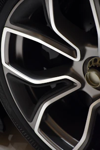 Close-up of a shiny silver car rim with a sleek modern design on a black background.