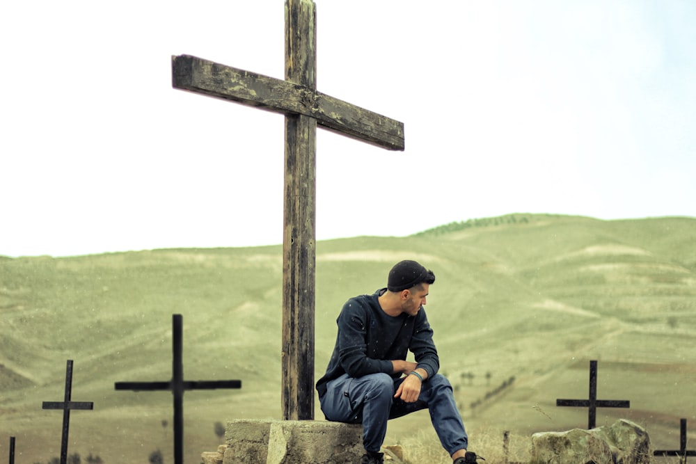man wearing black hoodie sitting on cross