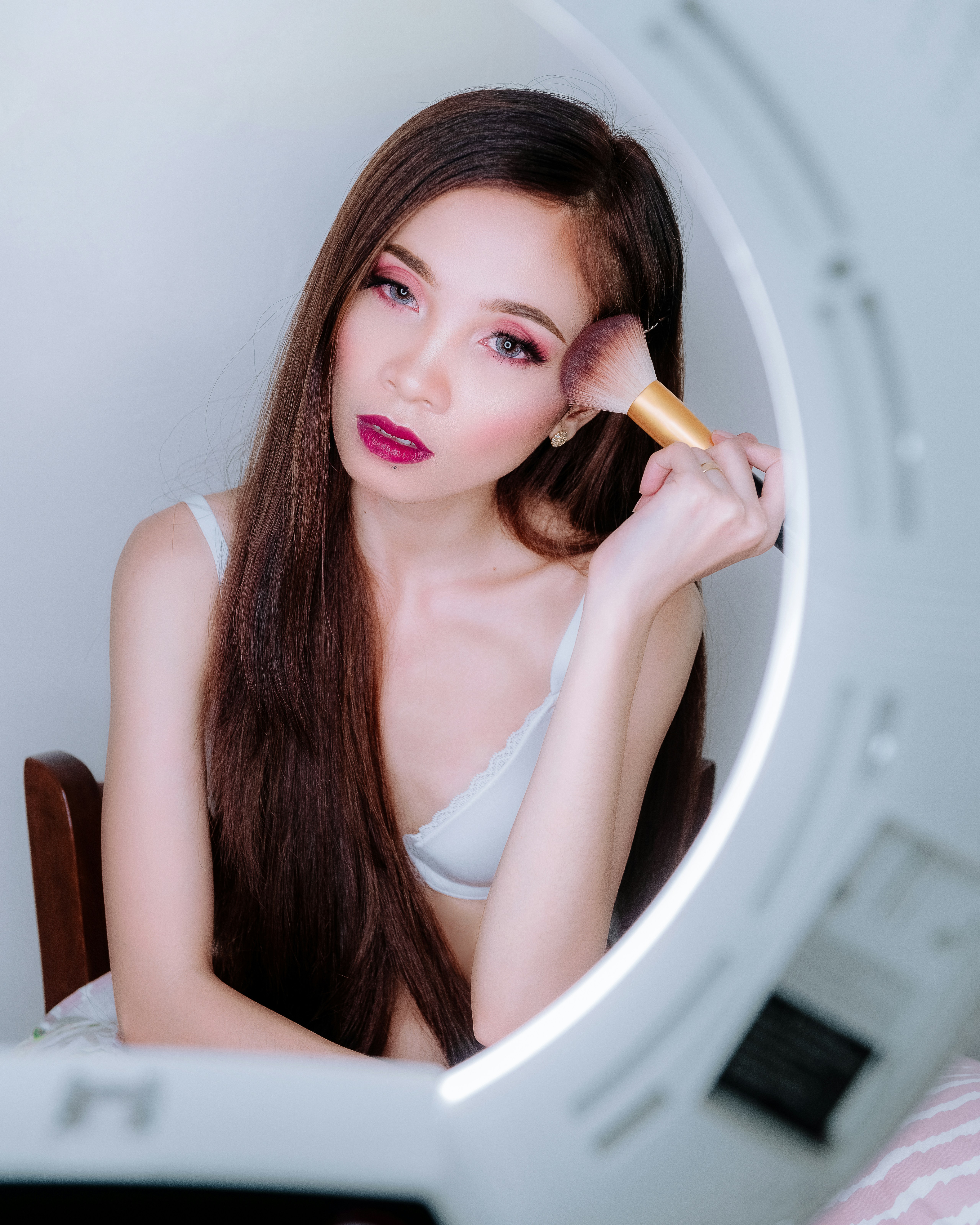 Frau trägt weißen BH mit Make-up-Pinsel