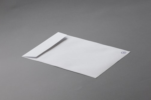 A white envelope with a minimalistic design lies on a smooth gray surface. The envelope features a simple logo or emblem in the top corner.