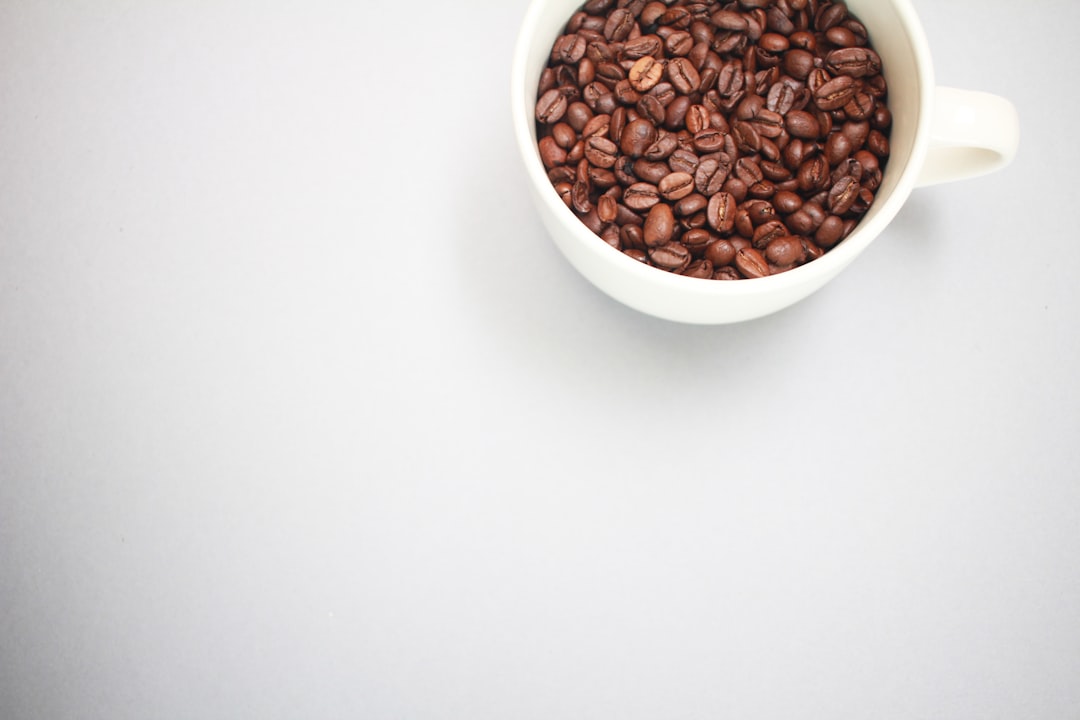 brown coffee beans in white ceramic mug