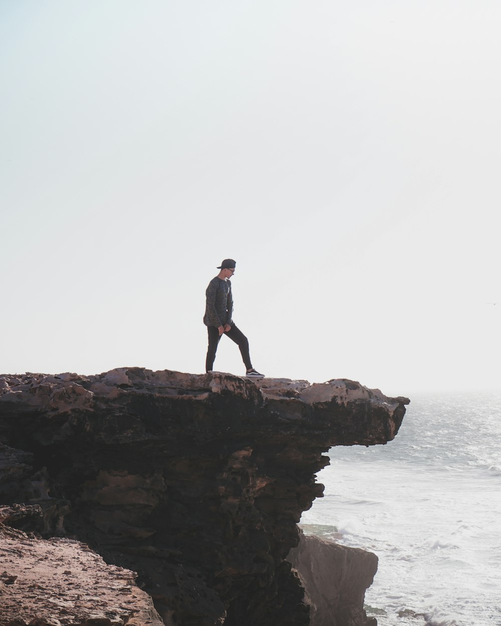 man standing beside mountain cliff during daytime