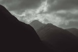 A dramatic overhead shot of a mountain range with clouds drifting between peaks.
