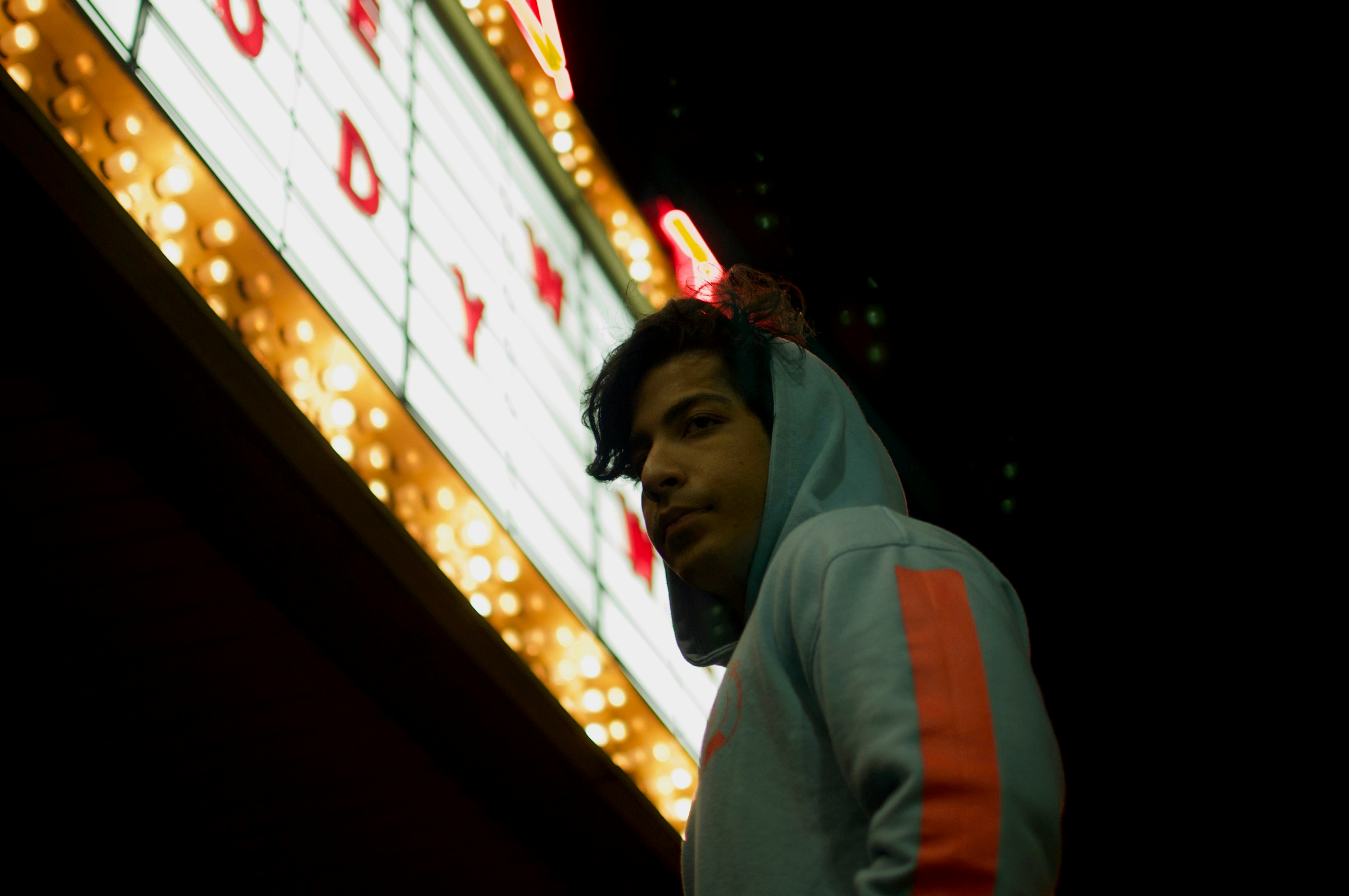 low-angle photography of man under a LED board signage