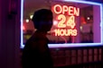 man standing beside open 24 hours signage during nighttime