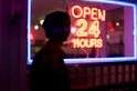man standing beside open 24 hours signage during nighttime