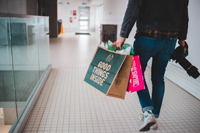 person walking while carrying a camera and paper bags
