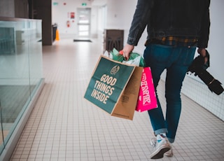 person walking while carrying a camera and paper bags