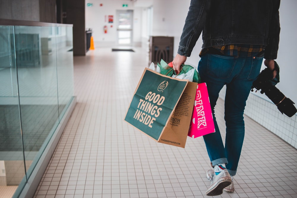 person walking while carrying a camera and paper bags