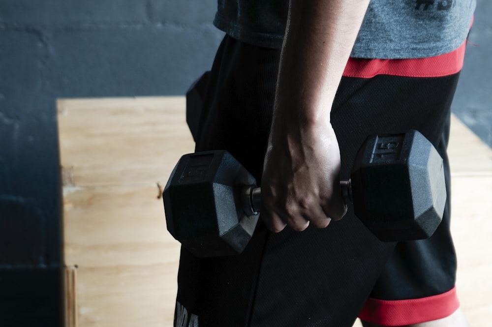 unknown person holding black dumbbell