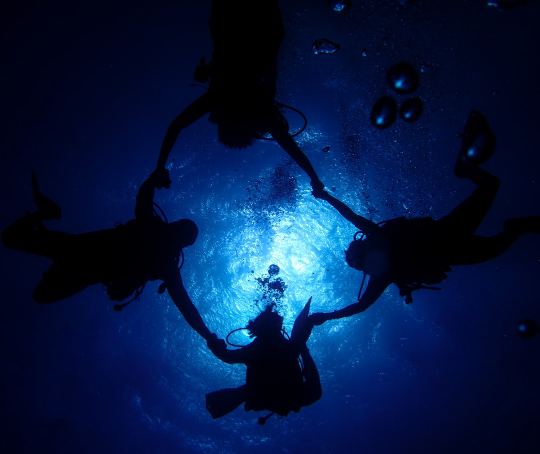 underwater photography of four scuba divers forming circle