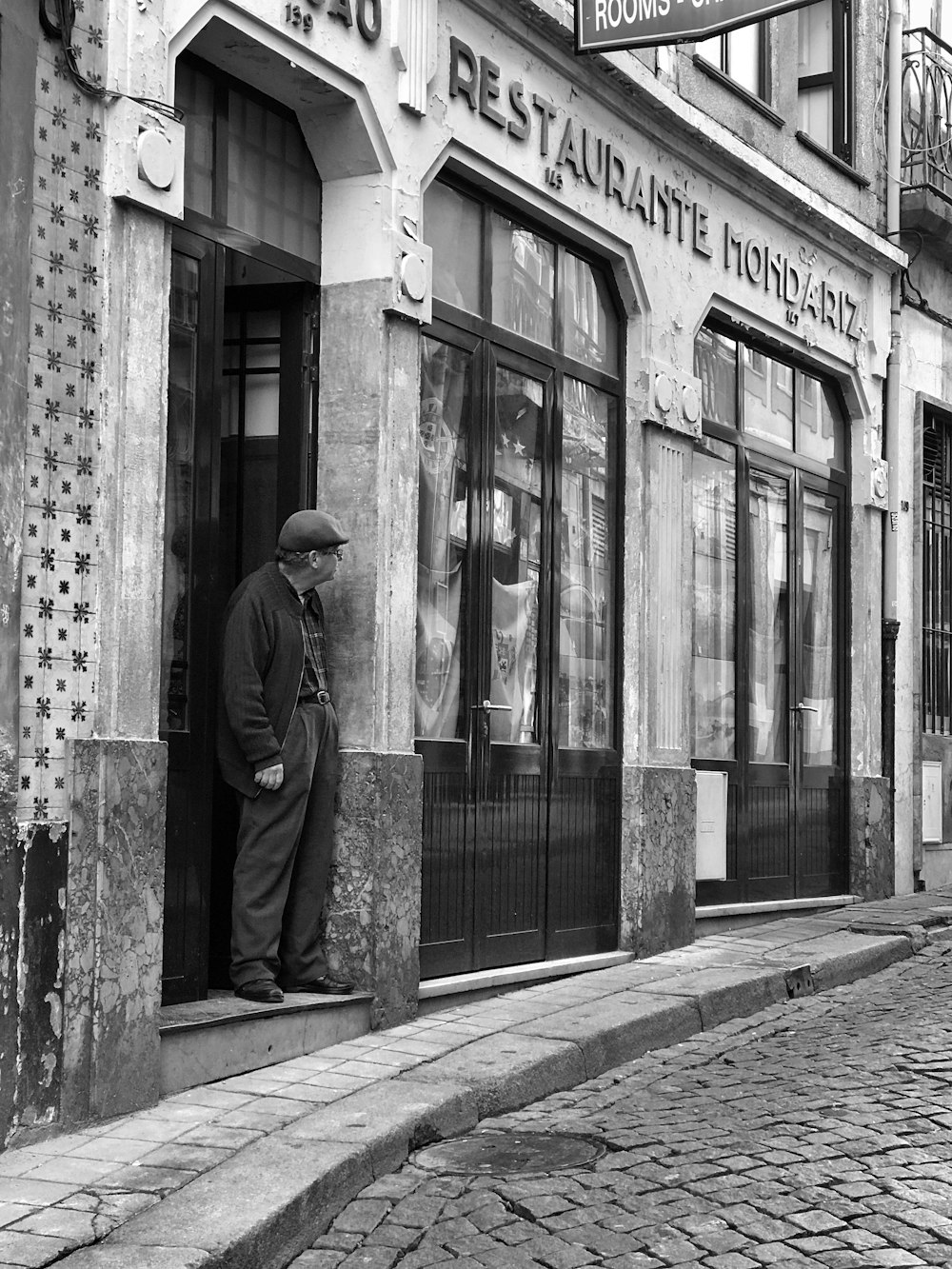 grayscale photography of man standing on doorway