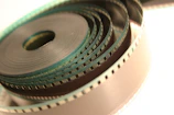 Close-up of a film reel intertwined with digital circuit patterns.