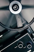 A close-up view of a film projector with a rotating reel. The image captures the mechanical components, including knobs labeled 'Framer' and 'Focus' and a visible part of the reel mid-spin.