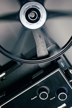 A close-up of a film reel spinning with sunlight filtering through trees.