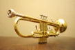 Close-up of shiny brass trumpets arranged neatly on a wooden shelf.