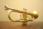 Close-up of shiny brass trumpets arranged neatly on a wooden shelf.