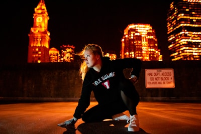 An athlete mid-stride on a city street at dusk, shadows stretching long under a midnight blue sky.