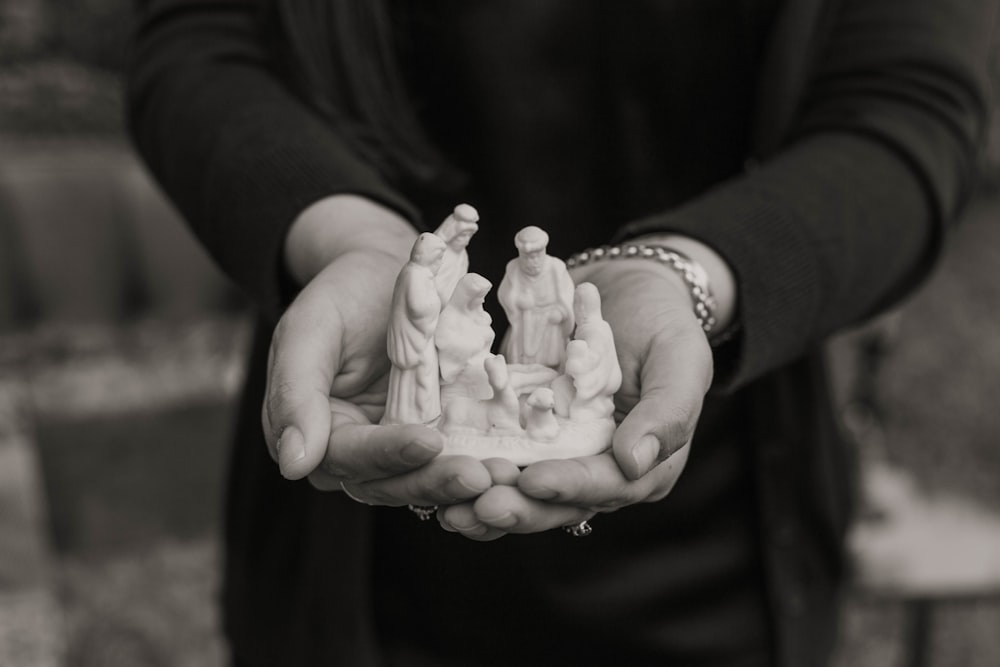 grayscale photo of person holding Nativity ceramic figurin