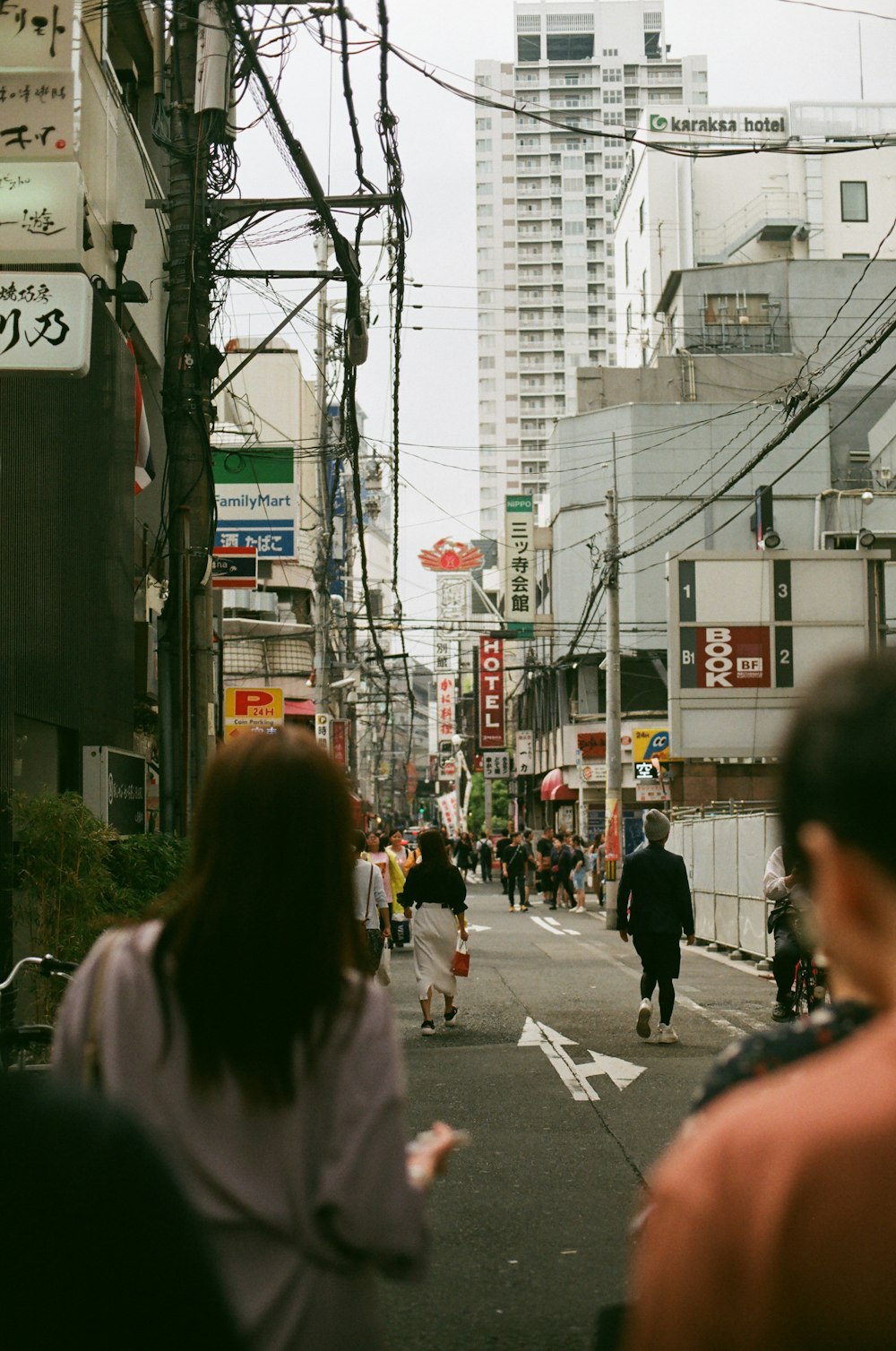 a group of people walking down a street next to tall buildings